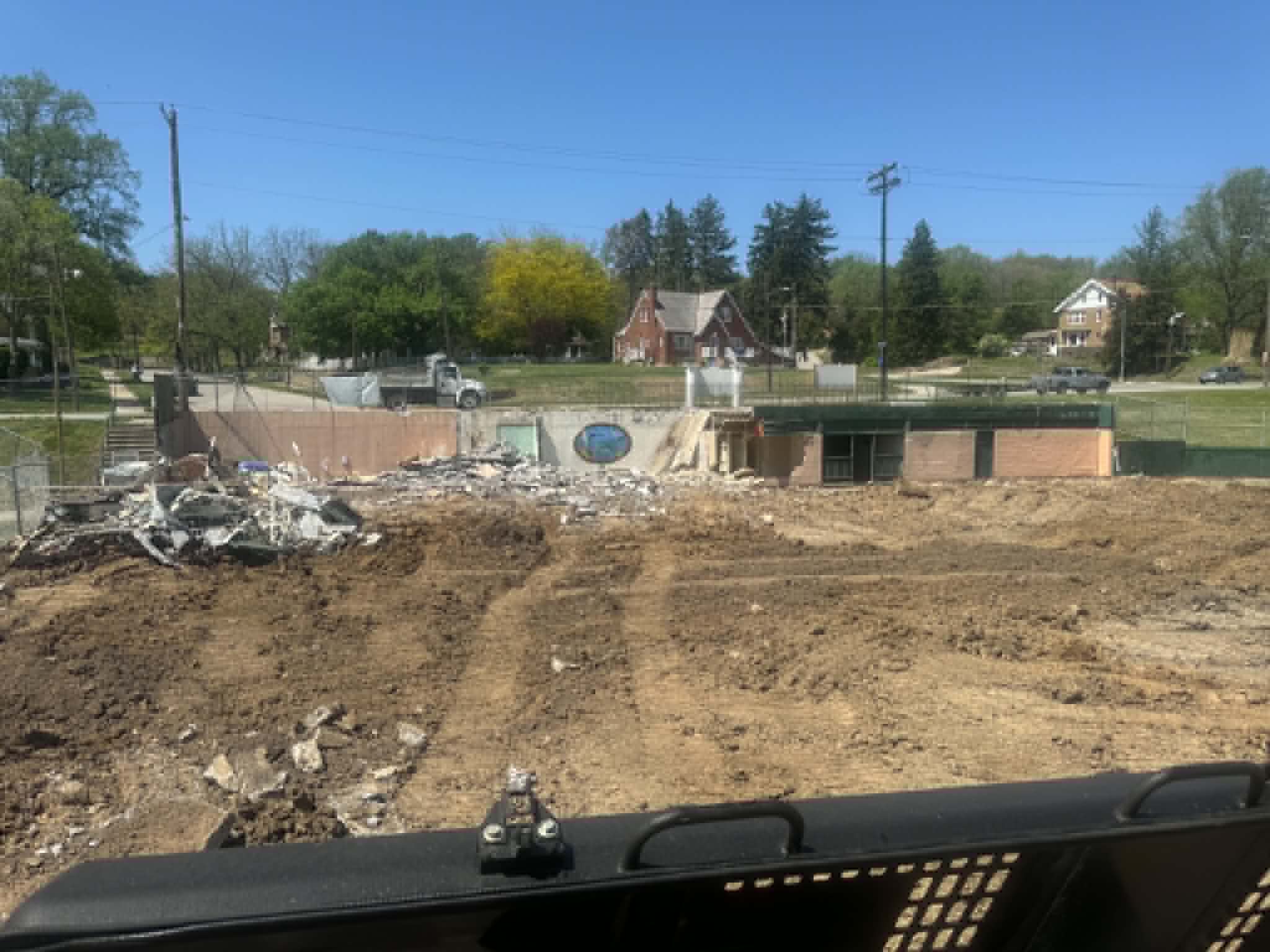 View from an excavator cab of a partially demolished brick building in a St. Joseph, Missouri neighborhood