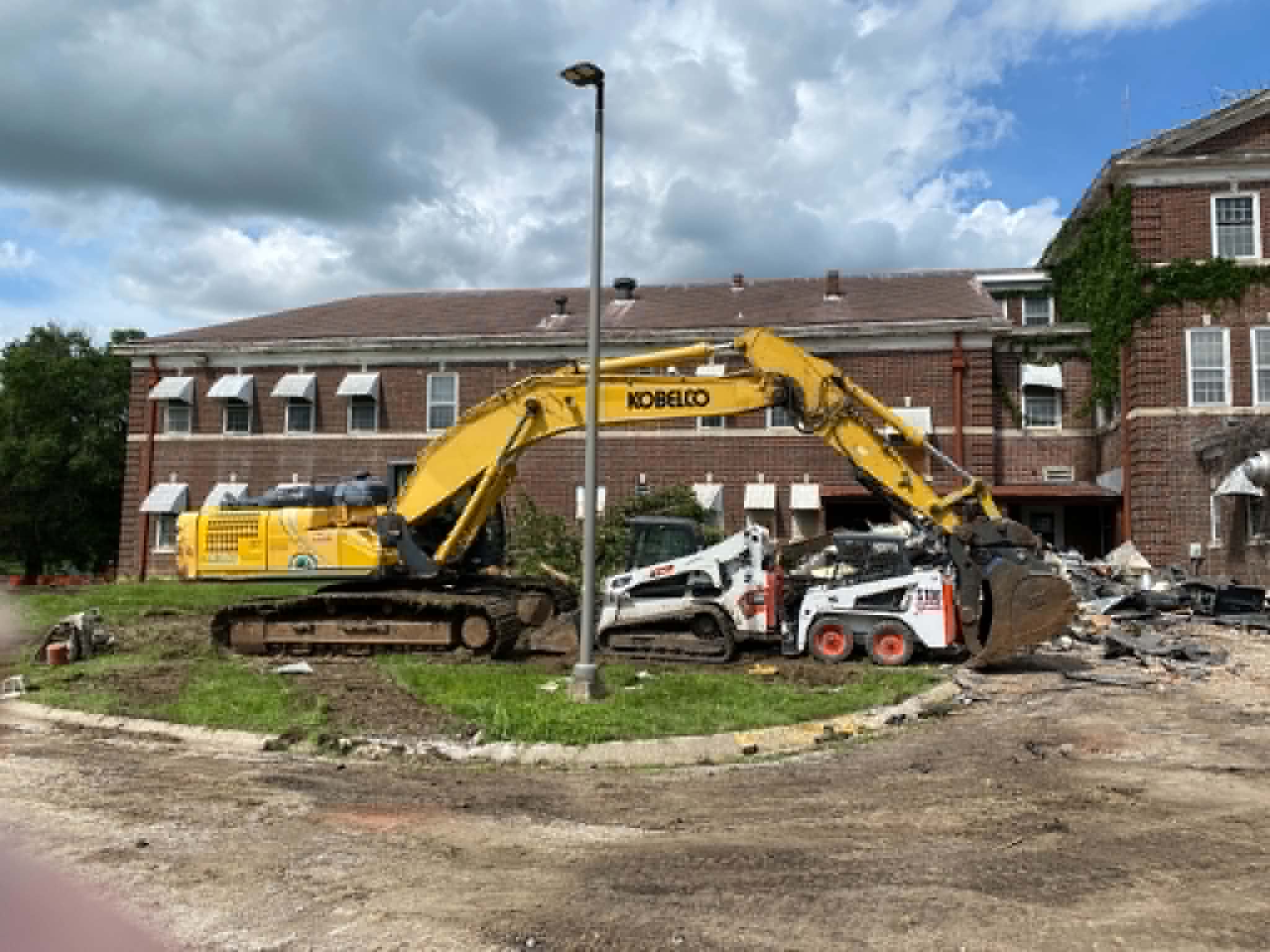 Excavator and skid steers working the demolition of the historic brick building in Kansas