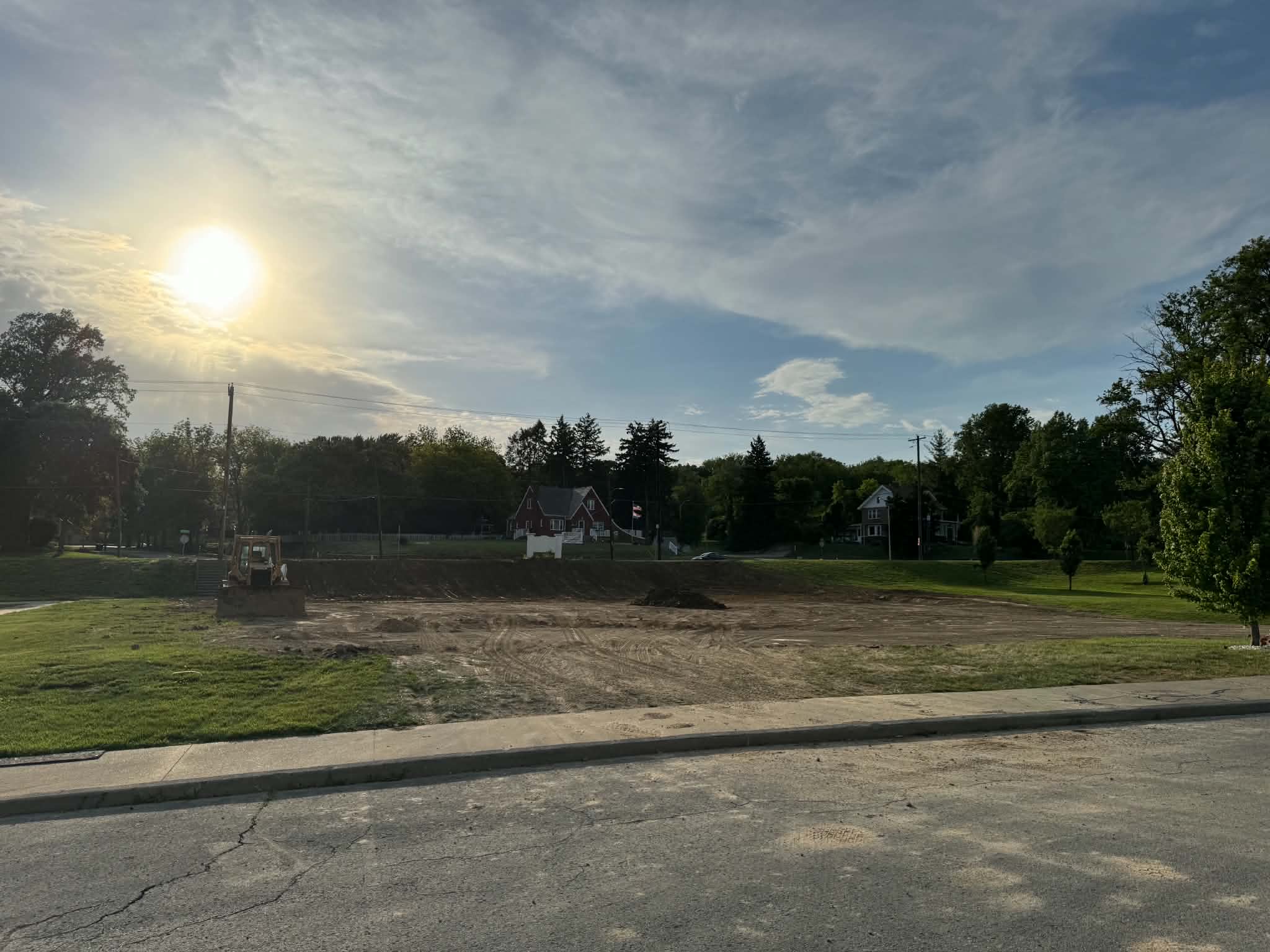 A cleared residential lot with a dozer at dusk following a site clearing project